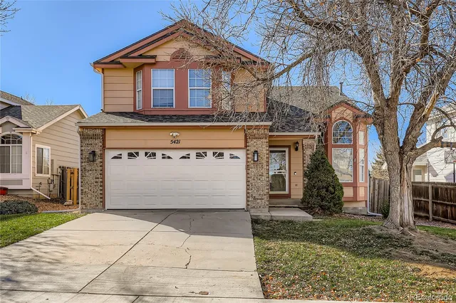 a front view of a house with a yard and trees