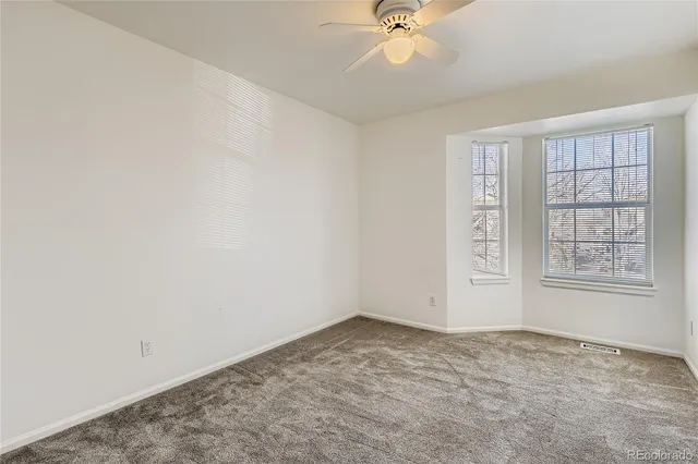 an empty room with a window and a fan