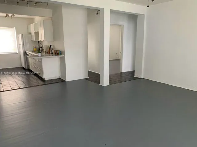 an empty room with kitchen and windows