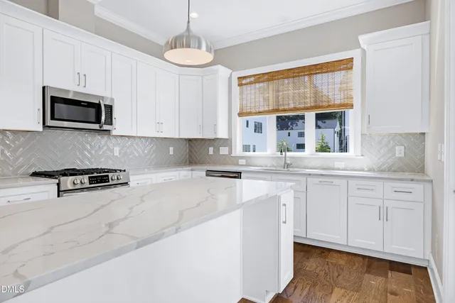 a kitchen with stainless steel appliances granite countertop a stove a sink and white cabinets