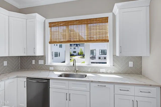 a kitchen with granite countertop a sink window and cabinets