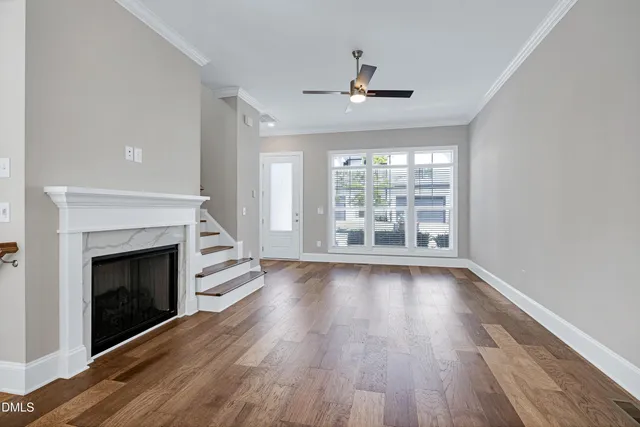 a view of an empty room with wooden floor fireplace and a window