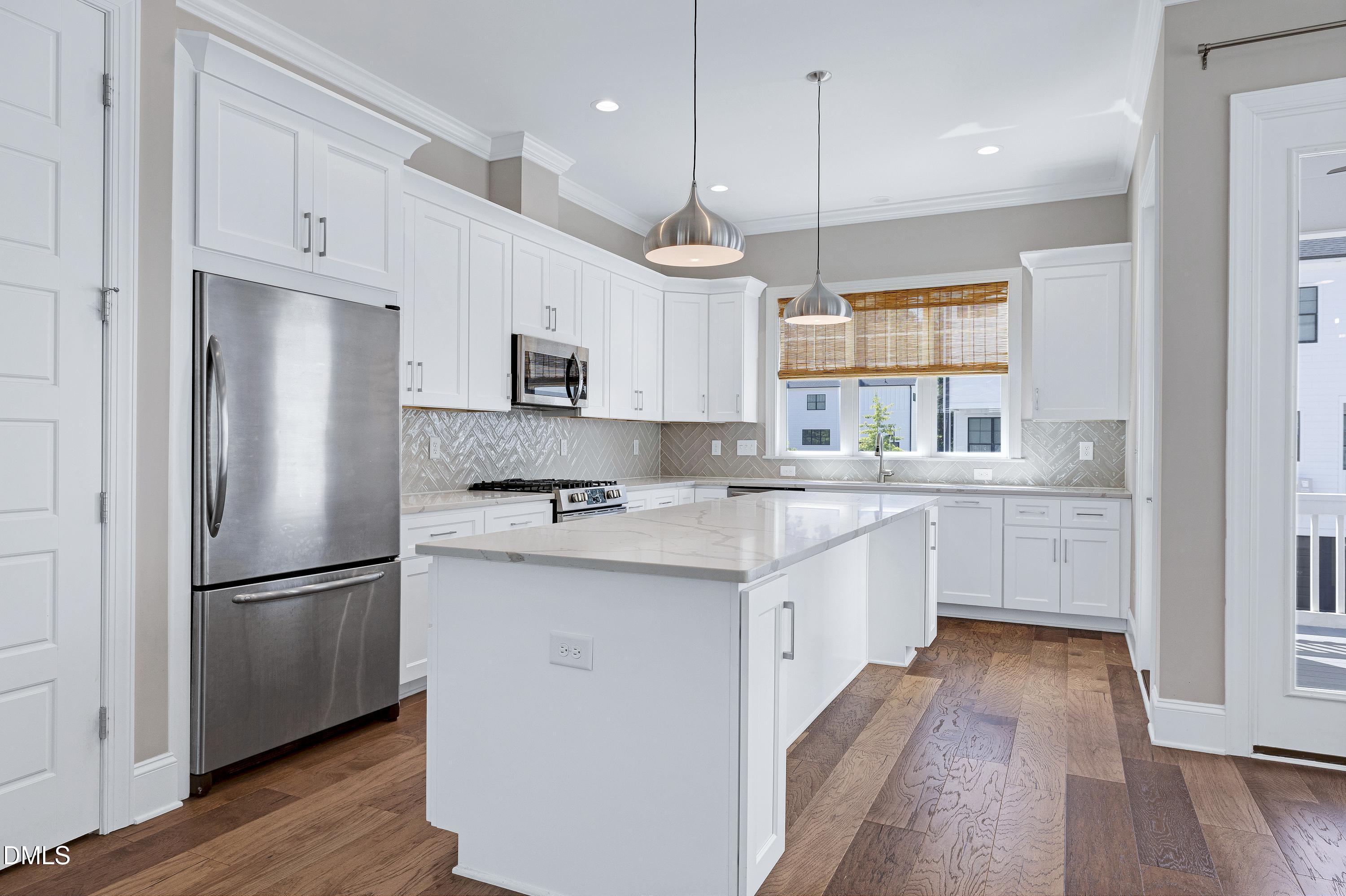 4909 Madone Drive Raleigh, NC 27606 - Photo 9 of 48 a kitchen with kitchen island white cabinets and stainless steel appliances
