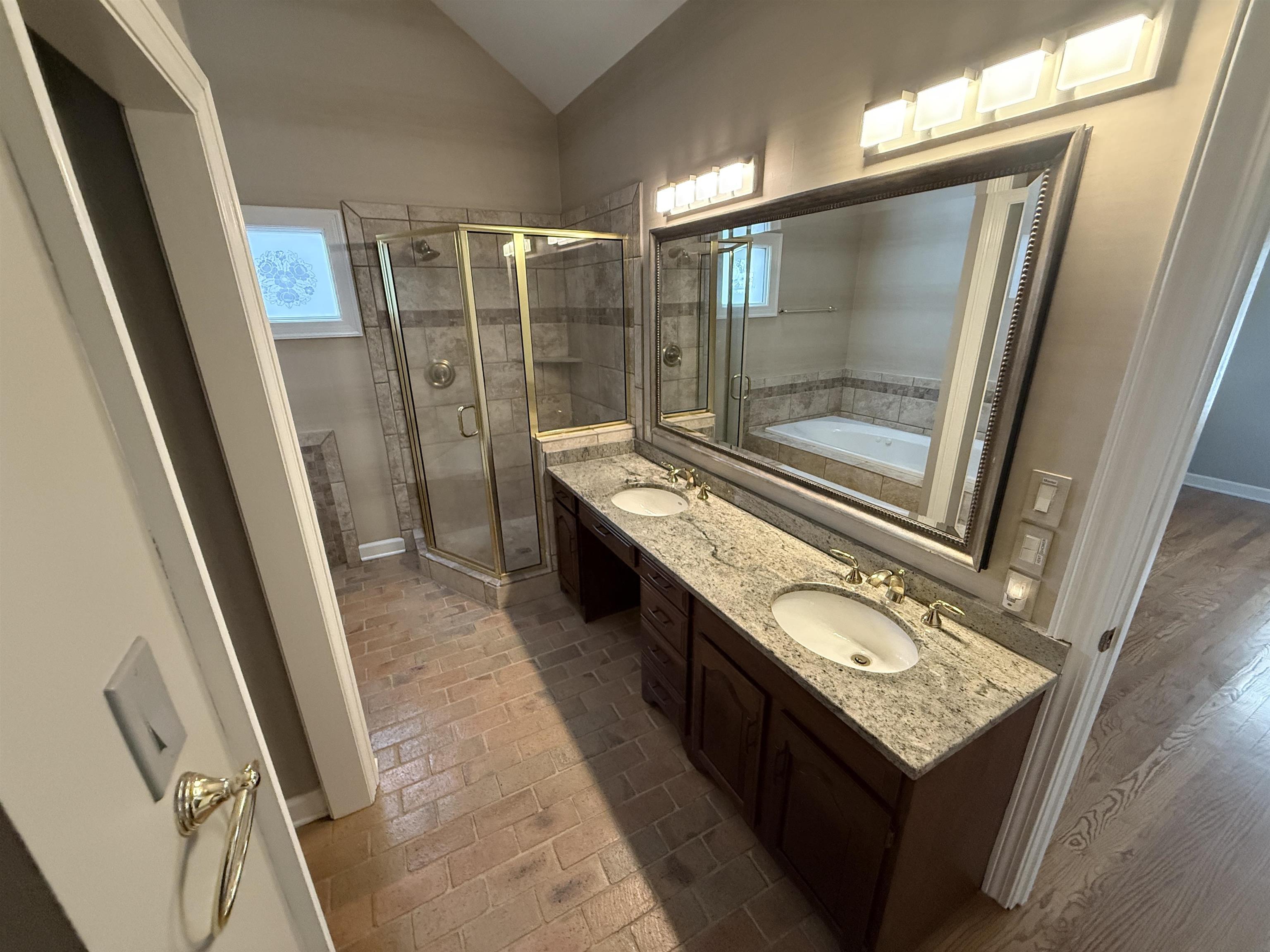 765 Sweetbrier Road Memphis, TN 38120 - Photo 14 of 33 Bathroom featuring double vanity, healthy amount of natural light, a shower stall, vaulted ceiling, and a garden tub