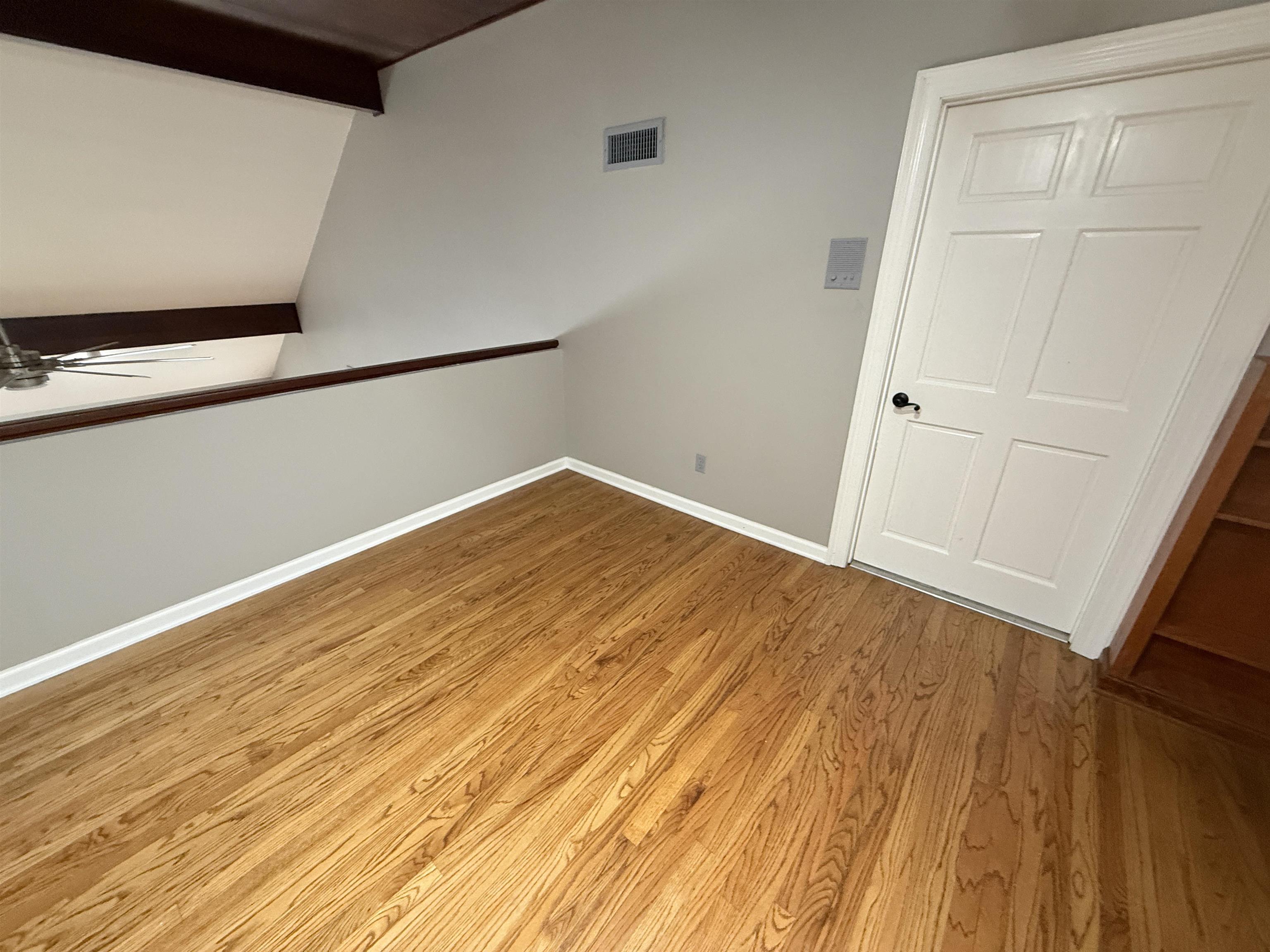 765 Sweetbrier Road Memphis, TN 38120 - Photo 18 of 33 Unfurnished room with wood finished floors, a ceiling fan, and lofted ceiling with beams