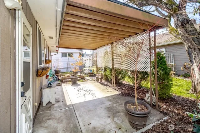 a view of a patio with table and chairs potted plants and floor to ceiling window