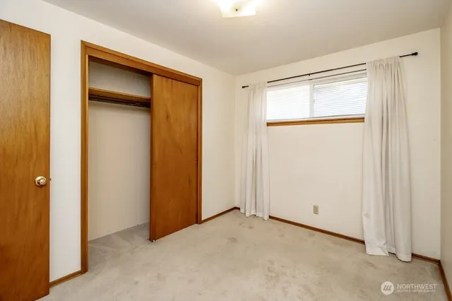 a view of an empty room with closet and a window