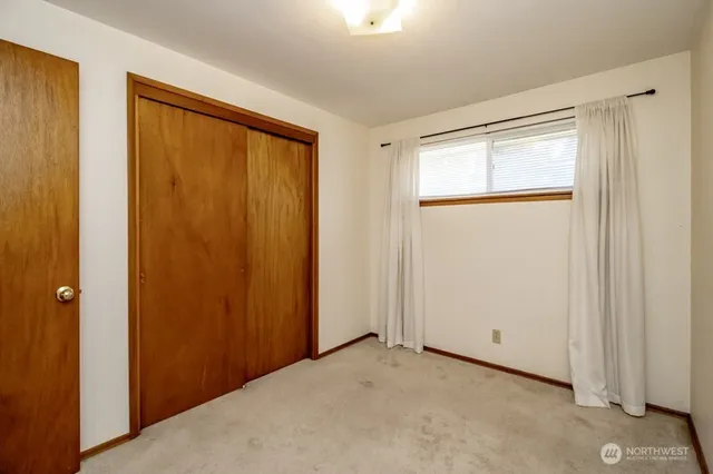 a view of an empty room with closet and a window
