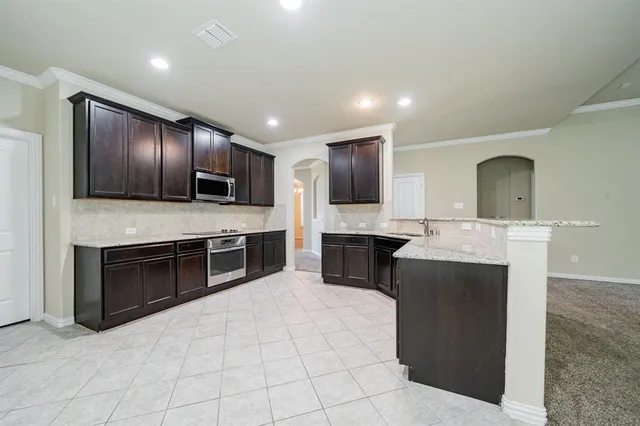a sink with granite countertop cabinets and window
