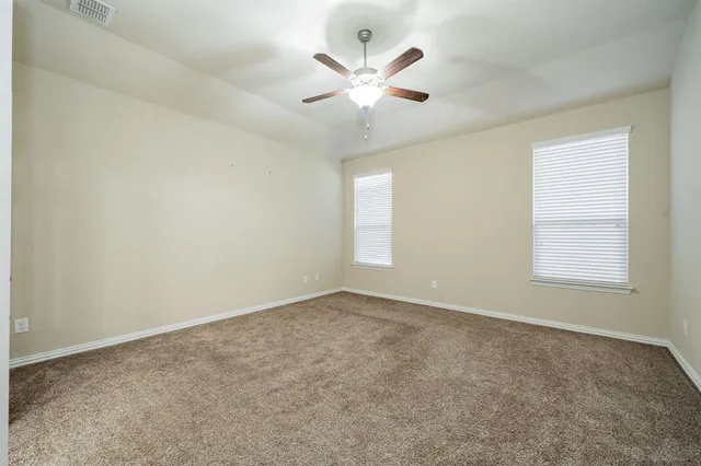 an empty room with chandelier fan and windows