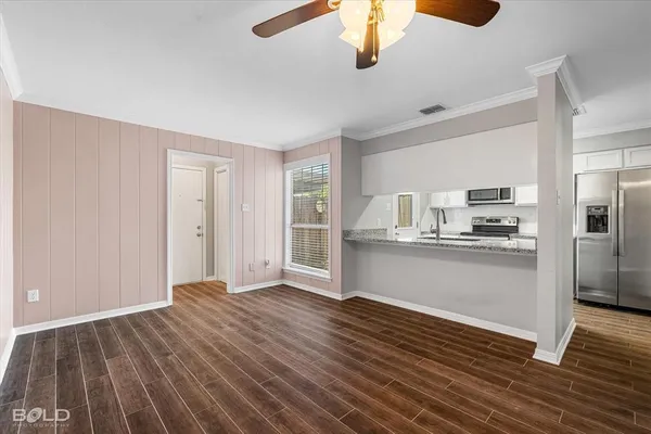 a view of kitchen and empty room with wooden floor