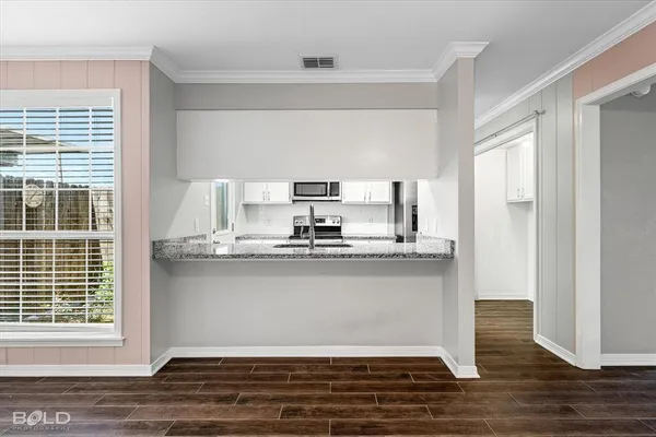 a kitchen with stainless steel appliances granite countertop a sink cabinets and wooden floor