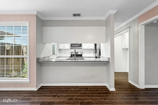 a kitchen with stainless steel appliances granite countertop a sink cabinets and wooden floor