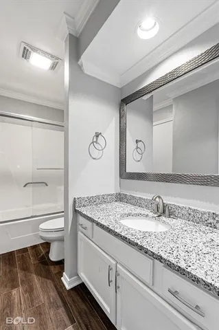a bathroom with a granite countertop sink a toilet and a shower