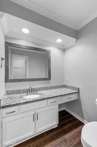 a bathroom with a granite countertop sink and a toilet