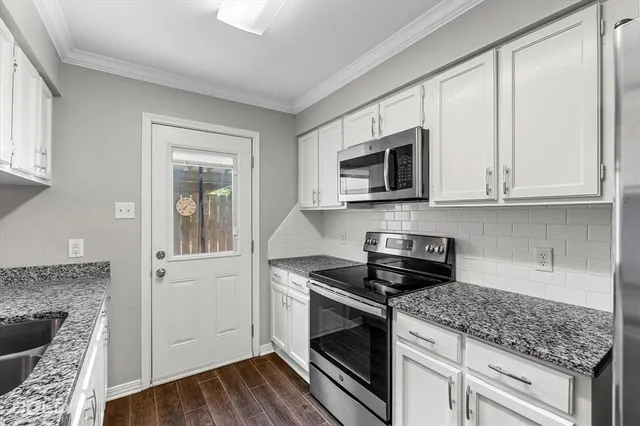 a kitchen with granite countertop a stove and a white cabinets