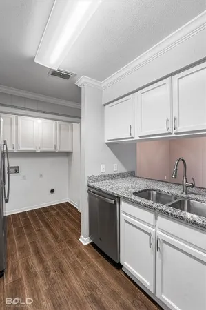 a kitchen with granite countertop a stove a sink dishwasher and cabinets with wooden floor