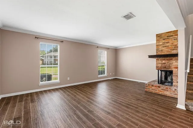 a view of empty room with wooden floor and fireplace