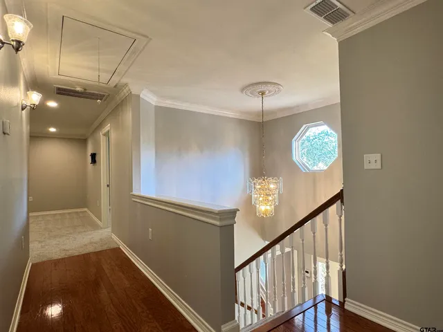 a view of a hallway with wooden floor and a chandelier