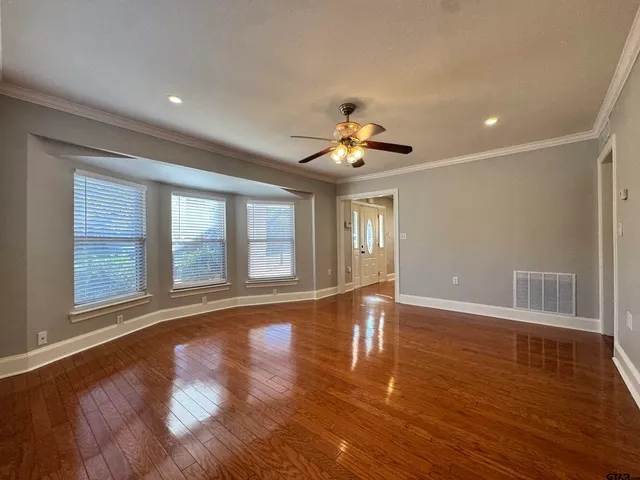 a view of an empty room with wooden floor and a window