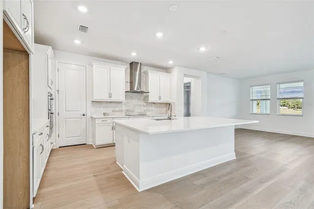 a large white kitchen with a stove a sink a refrigerator and cabinets