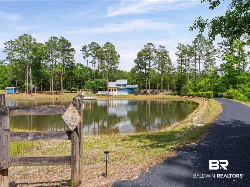3160 Old Castleberry Road Brewton, AL 36426 - Photo 27 of 36 Pond-front property featuring a private paved driveway, a wooden fence, and multiple structures