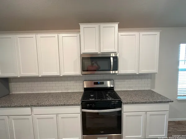 a kitchen with white cabinets and black appliances