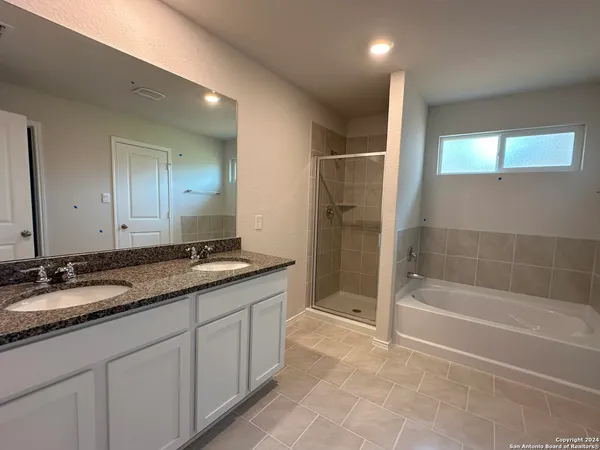 a spacious bathroom with a granite countertop sink a toilet a mirror and shower
