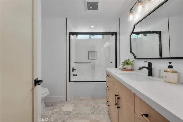 a bathroom with a granite countertop sink mirror and toilet