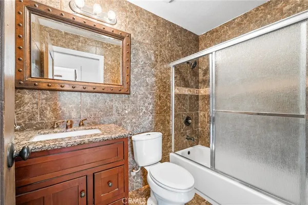 a bathroom with a granite countertop sink toilet and shower