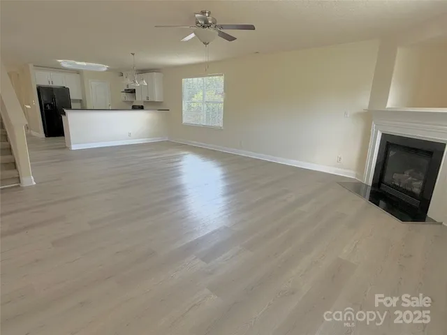 a view of a kitchen and an empty room with a fireplace