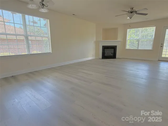 an empty room with windows fireplace and wooden floor