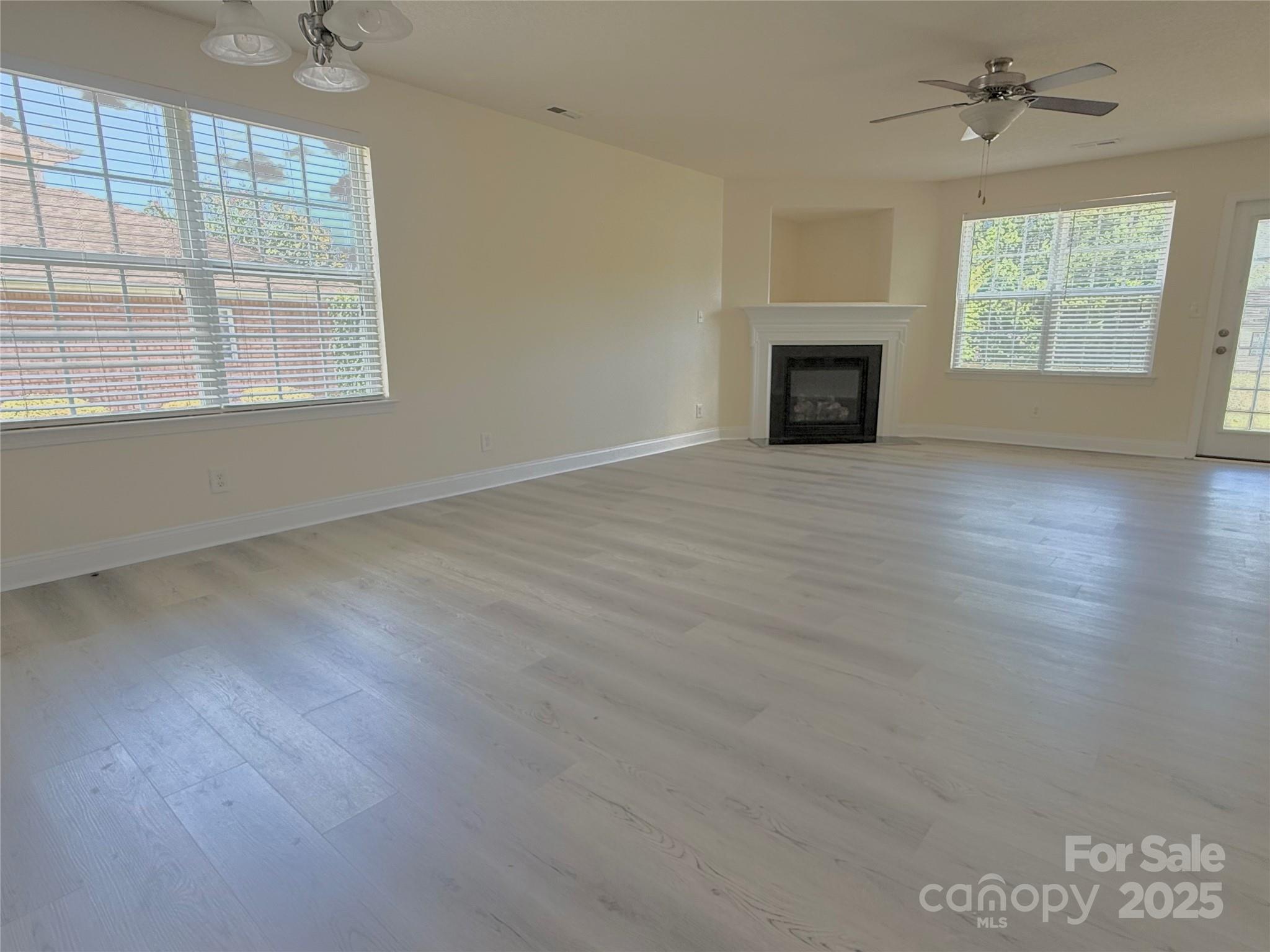 7534 April Mist Trail Huntersville, NC 28078 - Photo 13 of 47 an empty room with windows fireplace and wooden floor