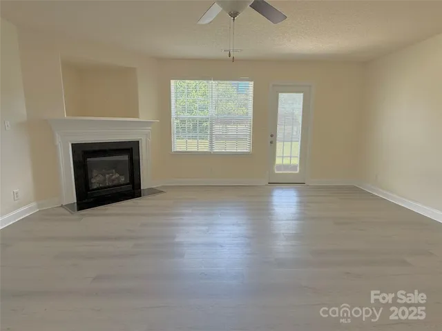 an empty room with wooden floor fireplace and windows