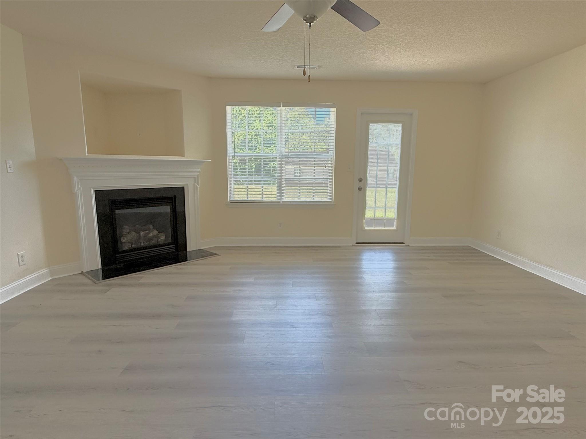 7534 April Mist Trail Huntersville, NC 28078 - Photo 14 of 47 an empty room with wooden floor fireplace and windows
