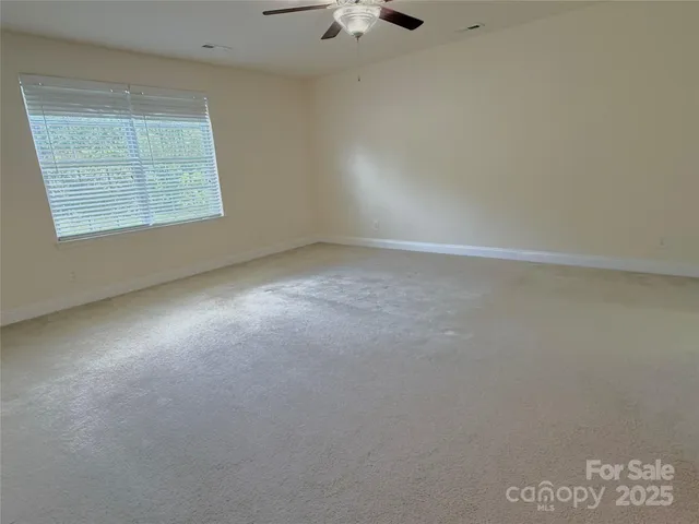 an empty room with a window and a ceiling fan