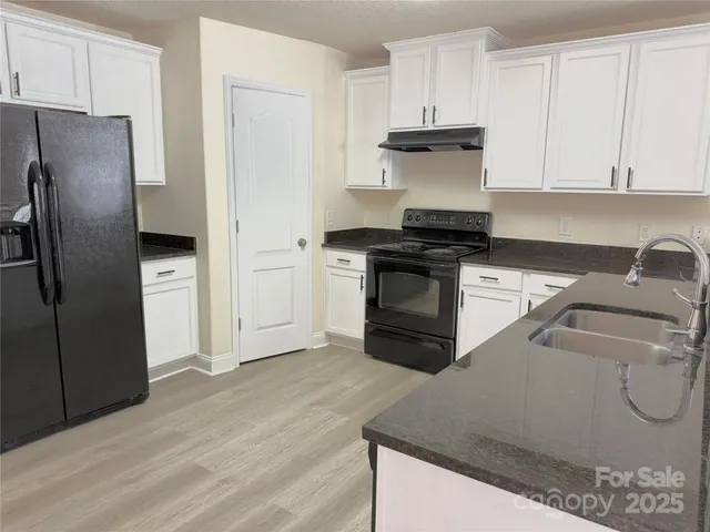 a kitchen with granite countertop a refrigerator stove and sink