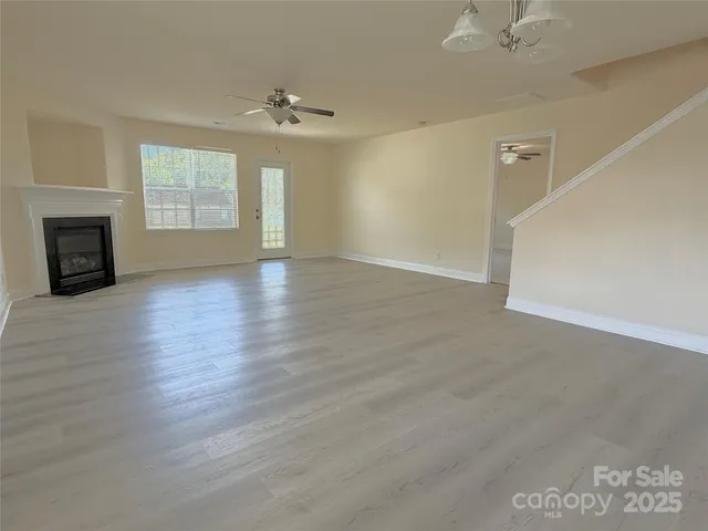 an empty room with wooden floor fireplace and windows
