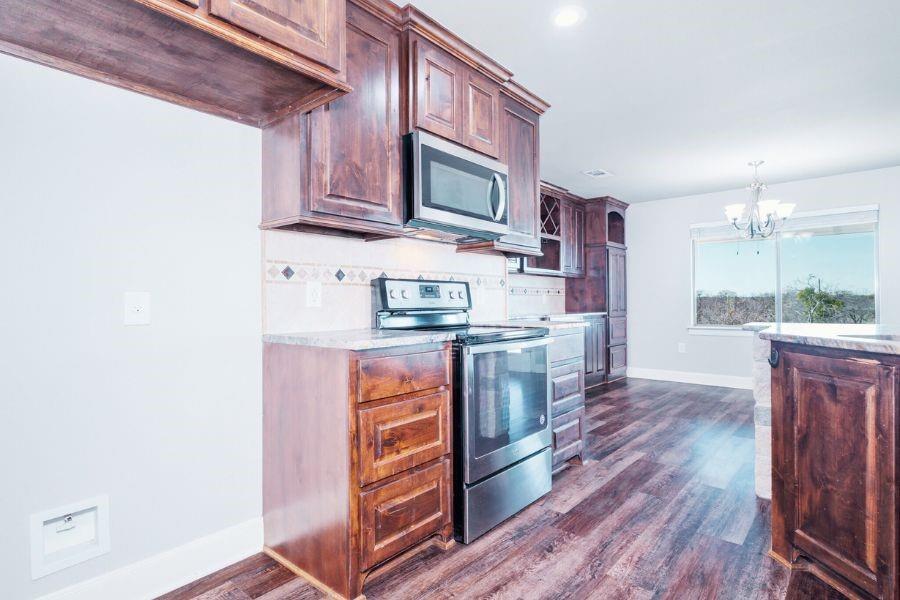 4319 County Road 337 Early, TX 76802 - Photo 9 of 31 Kitchen with stainless steel appliances, a chandelier, dark wood-style floors, tasteful backsplash, and pendant lighting