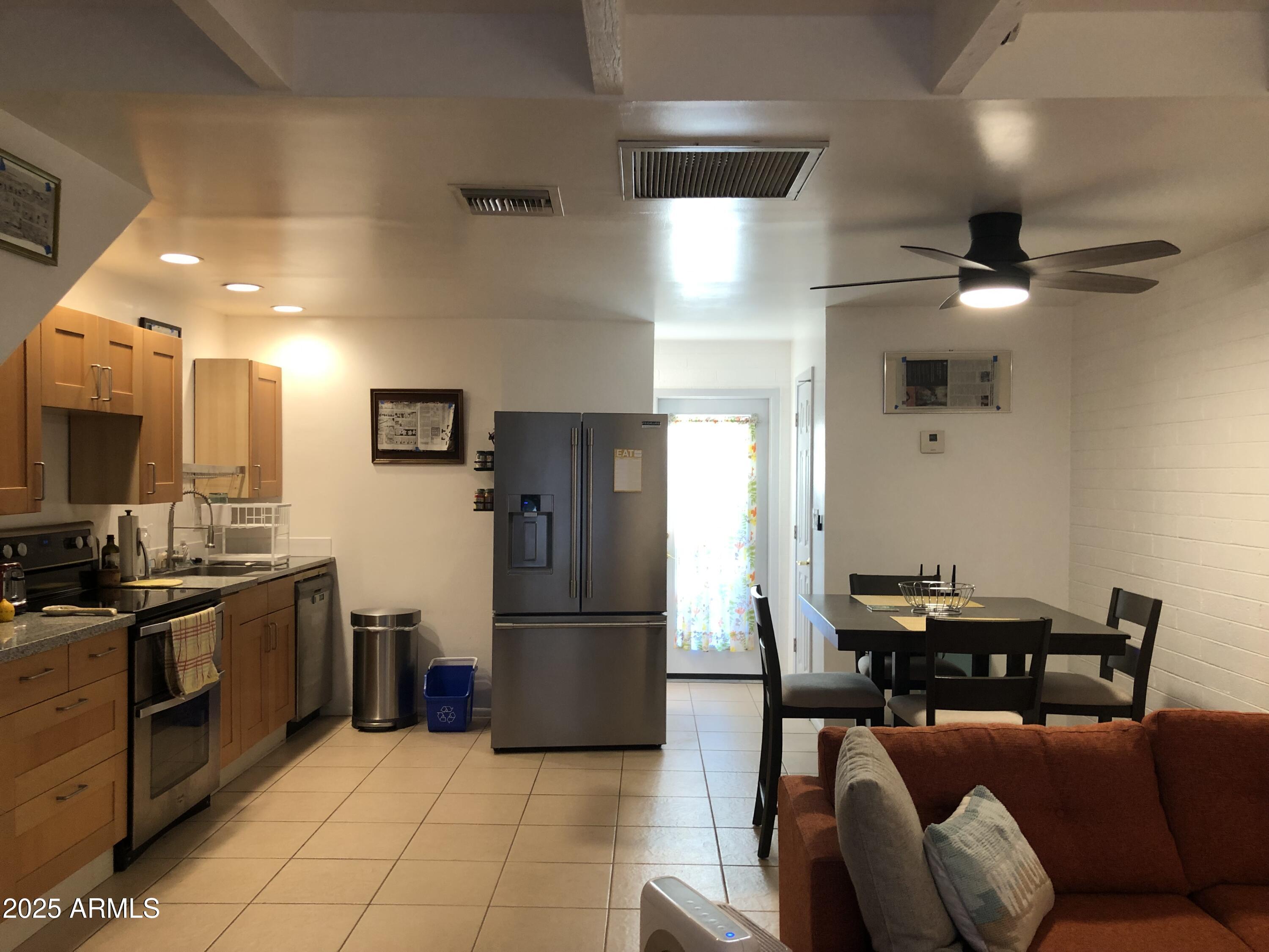 2025 South Granada Drive, Unit 12 Tempe, AZ 85282 - Photo 20 of 35 a kitchen with stainless steel appliances kitchen island granite countertop a refrigerator oven a sink a dining table and chairs with wooden floor