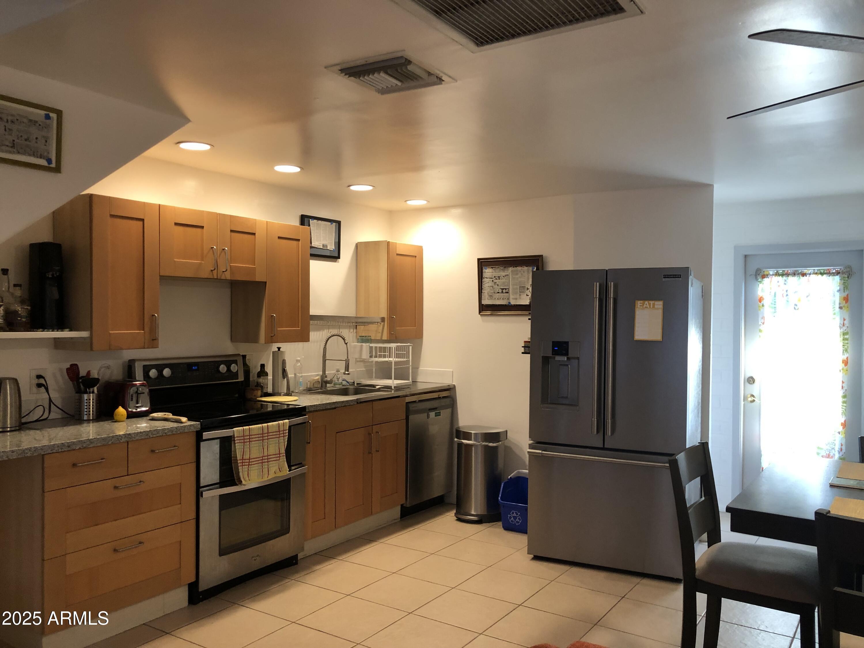 2025 South Granada Drive, Unit 12 Tempe, AZ 85282 - Photo 5 of 35 a kitchen with a refrigerator a stove top oven a sink and cabinets