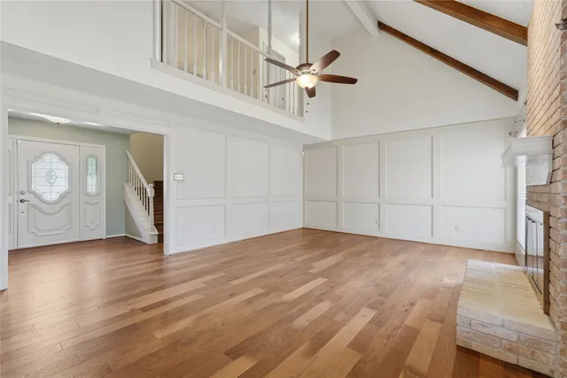 a view of a livingroom with wooden floor a ceiling fan and staircase