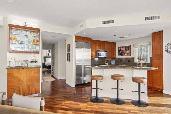 a kitchen with stainless steel appliances granite countertop a refrigerator a stove top oven and a dining table with wooden floor