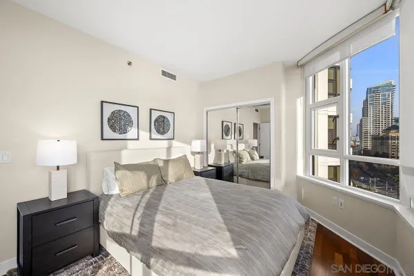 a spacious bedroom with a large window and a wooden floor