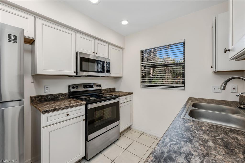 5191 Mahogany Ridge Drive Naples, FL 34119 - Photo 17 of 18 a kitchen with granite countertop a sink stove and microwave