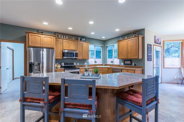 a kitchen with a refrigerator a stove a sink a dining table and chairs