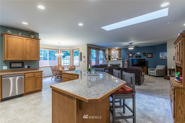 a kitchen with stainless steel appliances granite countertop a table chairs and a refrigerator