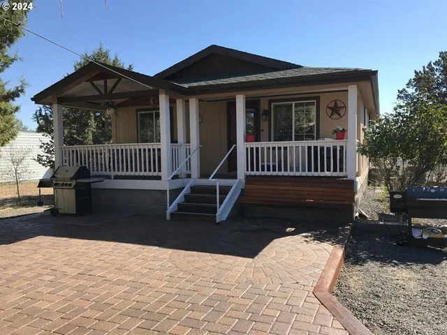 a view of a house with a yard and wooden bench