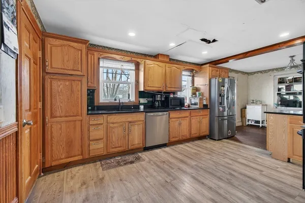 a kitchen with stainless steel appliances granite countertop a refrigerator a sink dishwasher a stove with wooden cabinets and floor