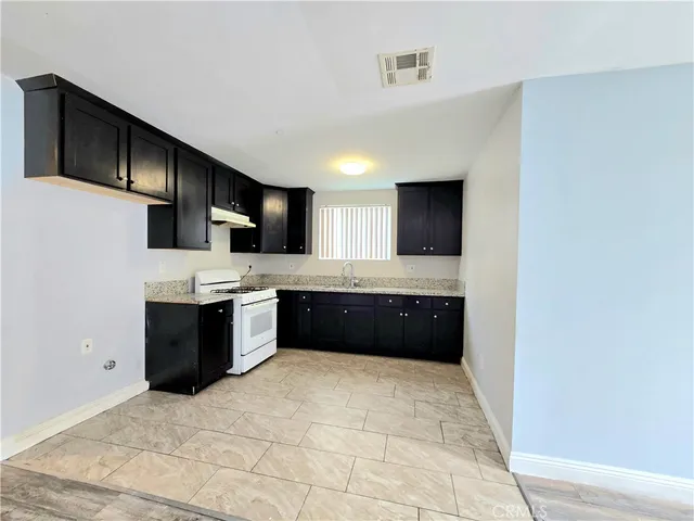 a large white kitchen with kitchen island granite countertop a sink a counter top space and stainless steel appliances